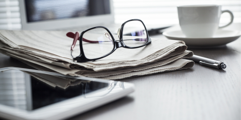 A pair of glasses placed on papers on a desk.
